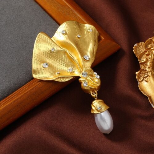 Vintage matte gold bow brooch with a faux pearl, perfect for coats and blazers.