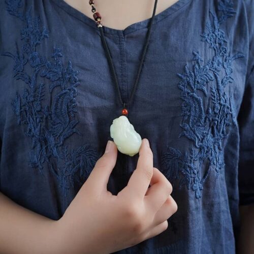 WoMan portant le collier à pendentifs Hotan Jade Pixiu, illustrant une taille substantielle et une présence puissante.