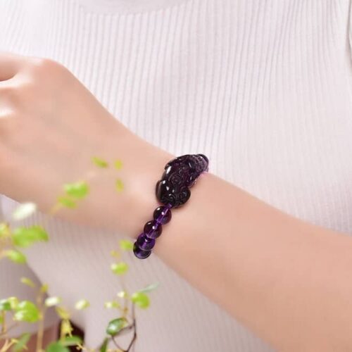 Le modèle porte le bracelet Amethyst Pixiu, illustrant l'élégance de la coupe et la couleur violette vibrante.